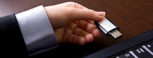 person holding memory stick by laptop