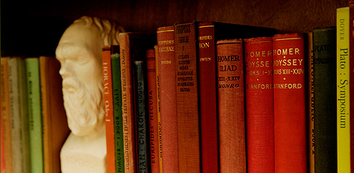a bookshelf containing classic works of literature and a statue bust bookend