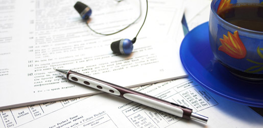 documents laid out flat with a pen, headphones and coffee cup sitting on top.