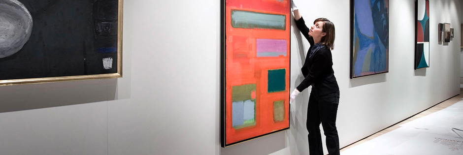Layla Bloom hangs a painting in the Stanley and Audrey Burton Gallery