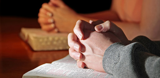 Hands at prayer resting on a book