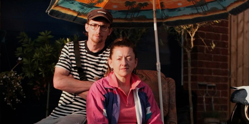 Jo Hartley sits with Brook Driver on set underneath an umbrella