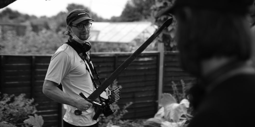 Brook Driver holds a prop sword on a film set