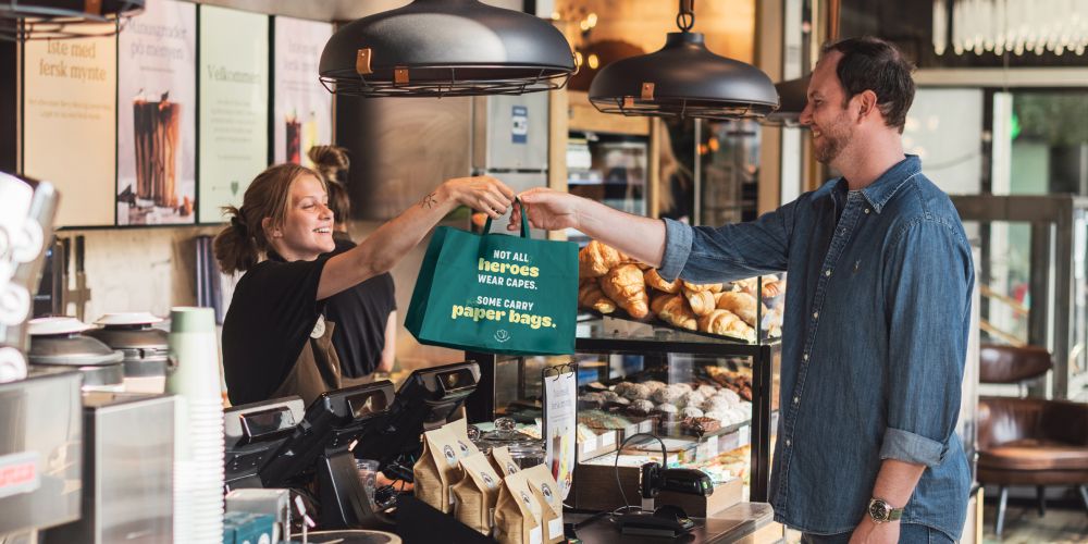 A cafe customer receives a surprise bag from the waitress over the counter