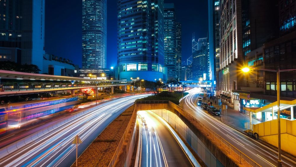 Time-lapse photograph showing the blur of car lights as they travel at night through a high rise city.