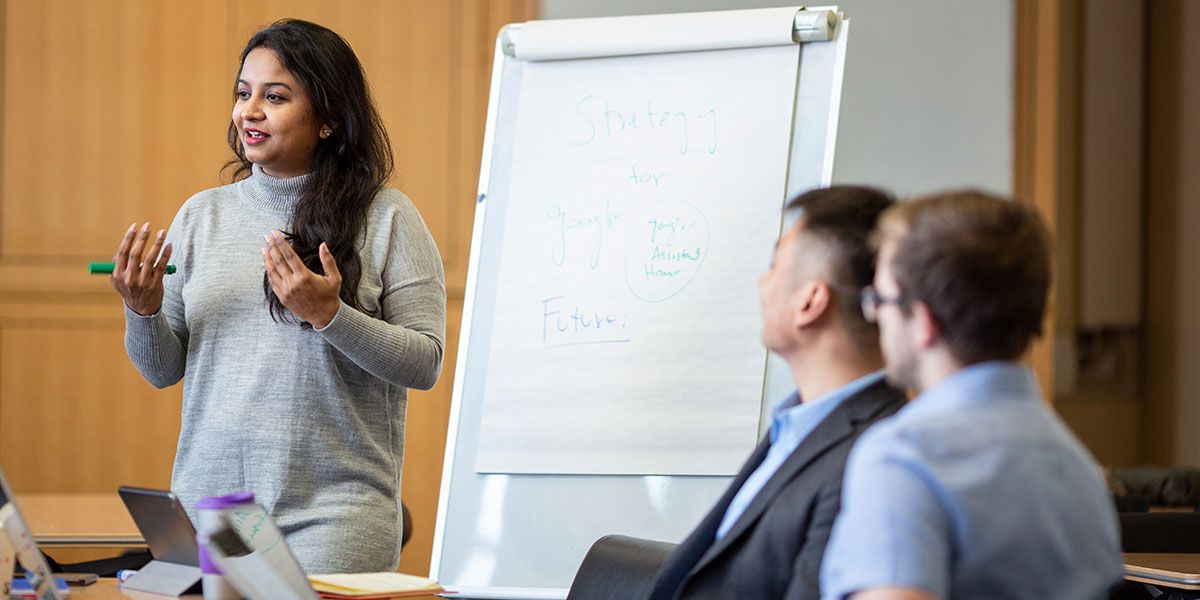 Female masters student presenting to a group in the Maurice Keyworth boardroom