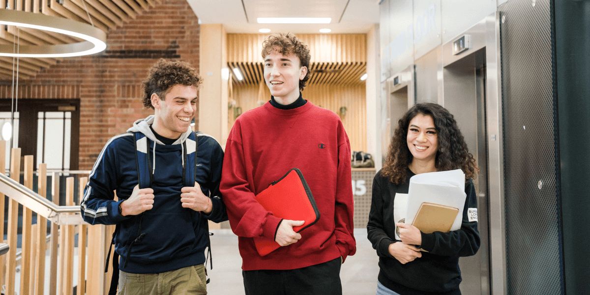 Three students walk through a corridor in the Sir William Henry Bragg building.