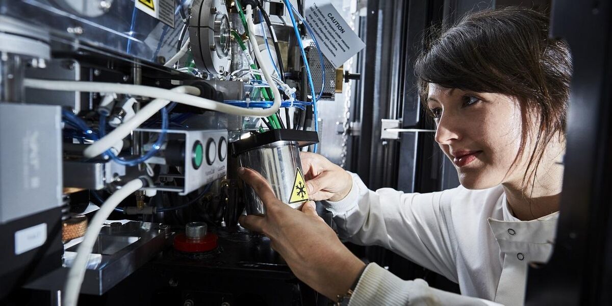 A researcher in lab coat operating an electron microscope