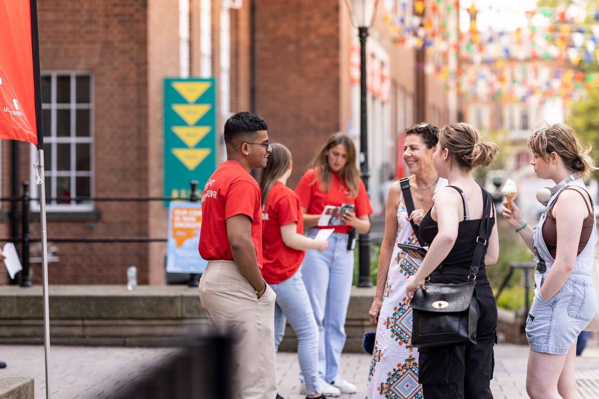 Visitors at Open Day outside the Leeds University Union building, chatting to a group of student ambassadors in red t-shirts.