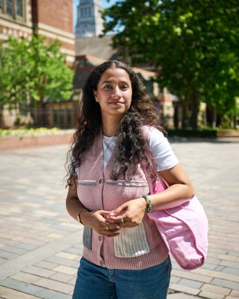 Pragya Sharma stood on campus by redbrick buildings and trees