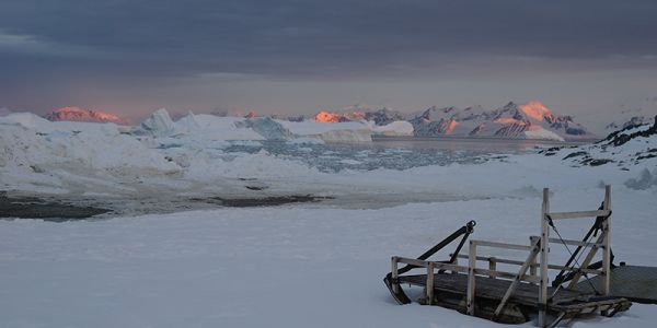 The late summer sun sets over mountains and icebergs around Adelaide Island, Antarctic Peninsula, as twenty-four hour daylight gives way to the long polar night of winter
