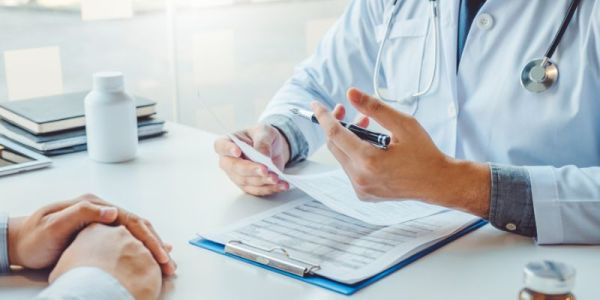 A doctor and patient sit and talk about medication.