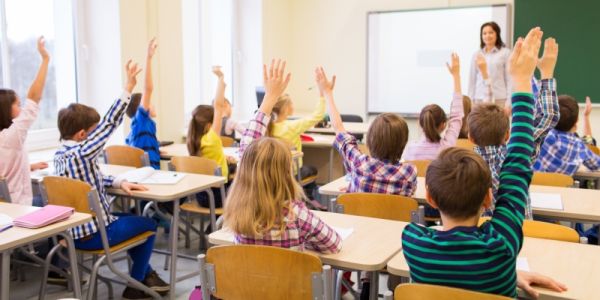 Children in a classroom raising their hands