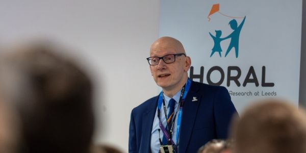 Professor Adam Glaser in front of the CHORAL logo speaking at the launch event for the partnership