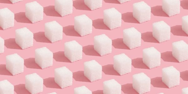 Sugar cubes lined up in rows on a pink background