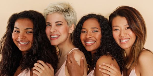 Four women with different skin tones looking at the camera
