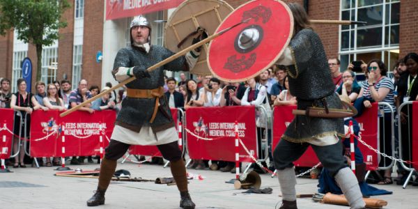 Two people dressed in medieval armour reenacting a battle