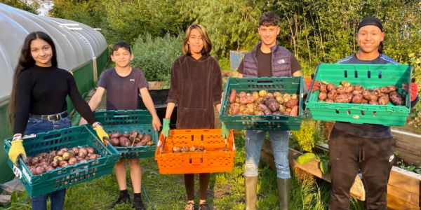 A group of young people holding fresh vegetables