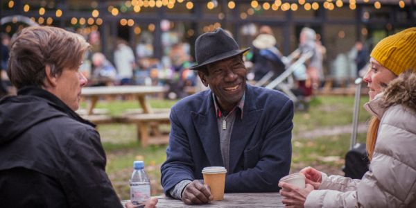 Three people sitting at a table smiling and drinking coffee