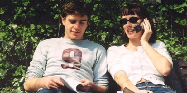 Two students on a bench, one using mobile phone