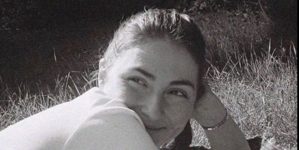 A black and white image of Anna May smiling, lying down, resting her head on her hand