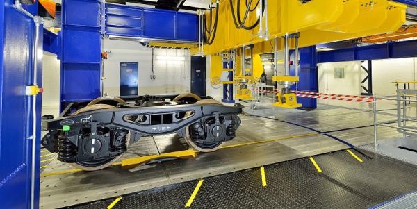 The image shows a set of train wheels on an indoor testring rig at the University of Huddersfield