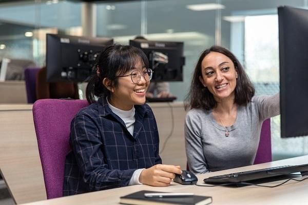 Two students look at a computer screen.