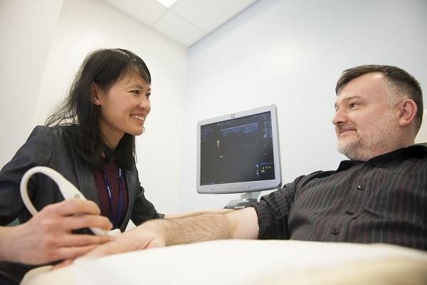 A doctor performing an ultrasound on a patient&#039;s hand in a hospital