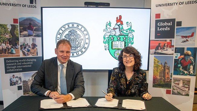 Professor Dr. Hauke Heekeren and Professor Simone Buitendijk sign a document while seated at a table.