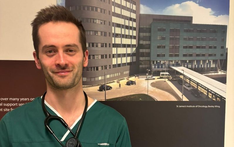 Jonathan Harris is pictured in front of a board displaying a graphic of St James' Hospital