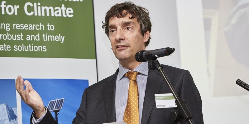 A head and shoulders shot of Professor Piers Forster stood behind a microphone on a stand.