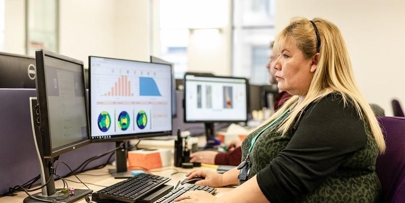 A software engineer looking at computer screens with graphs and charts on