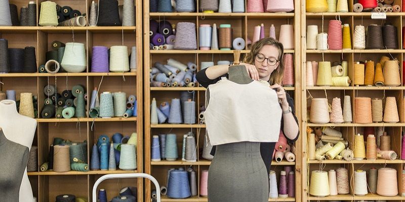 A student in the School of Design, pinning fabric on a mannequin.