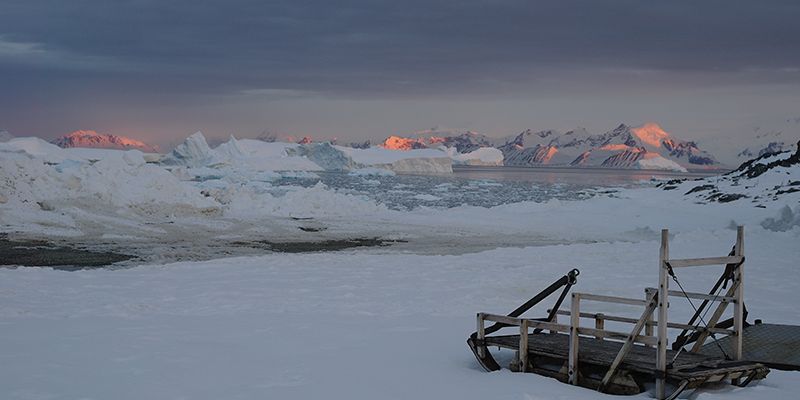 The late summer sun sets over mountains and icebergs around Adelaide Island, Antarctic Peninsula, as twenty-four hour daylight gives way to the long polar night of winter