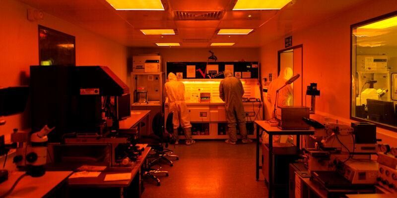 A clean room with three people working in protective suits.