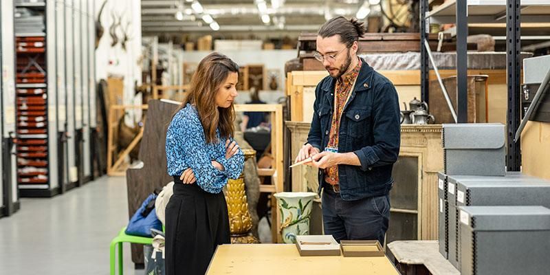 Two people standing by a table in a showroom. One is holding a label