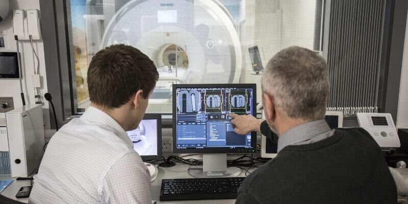 Two people sitting at a desk, looking at a computer screen in the Advanced Imaging Centre.