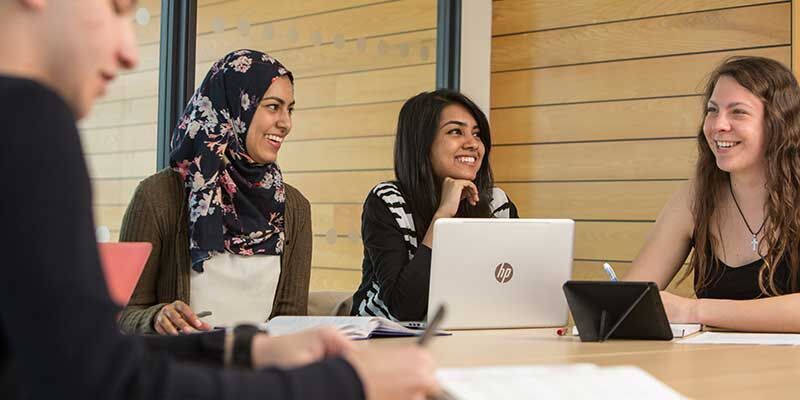 Students working together around a table with laptops