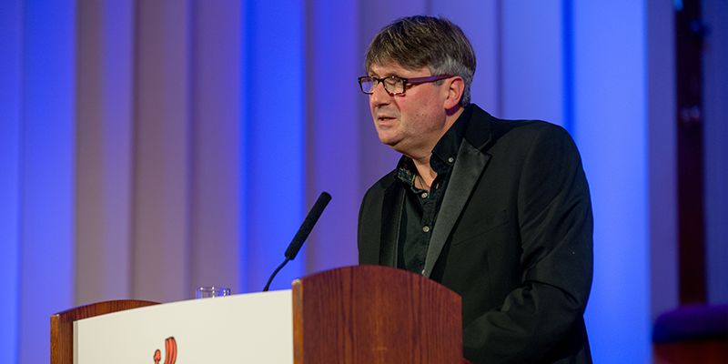 Simon Armitage stood at a University of Leeds lectern