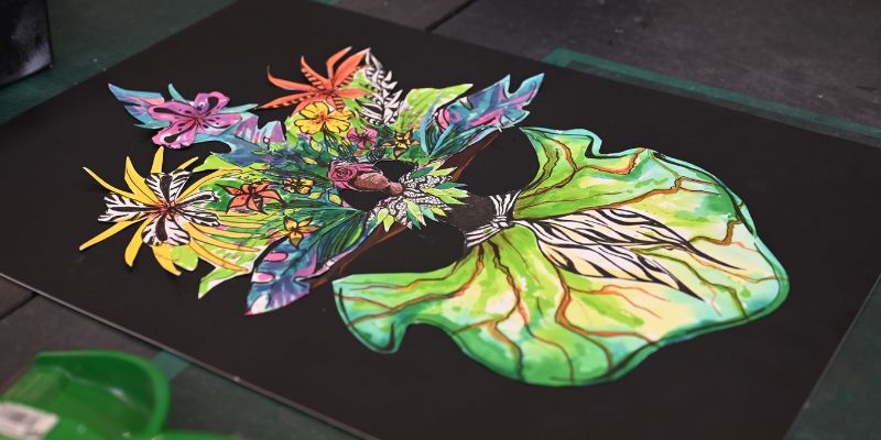 A sketch of a colourful carnival costume, with floral elements around the headpiece and a green, leaf-like skirt that billows out.
