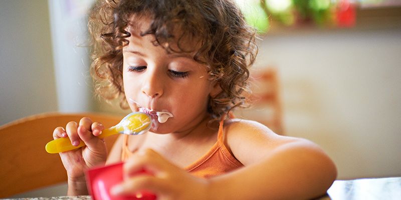 Child eating yogurt at dining room table