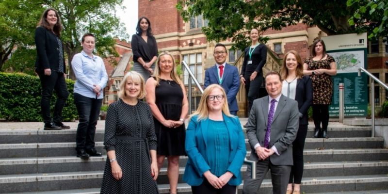 Eight fellows on exterior steps, joined by senior academics.