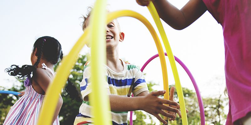 Young children enjoying playing with hula hoops.