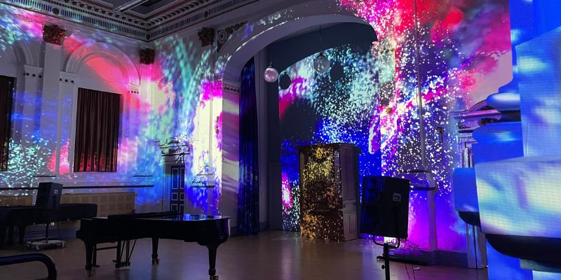 A concert hall is lit up with vibrant purples, pinks and blues
