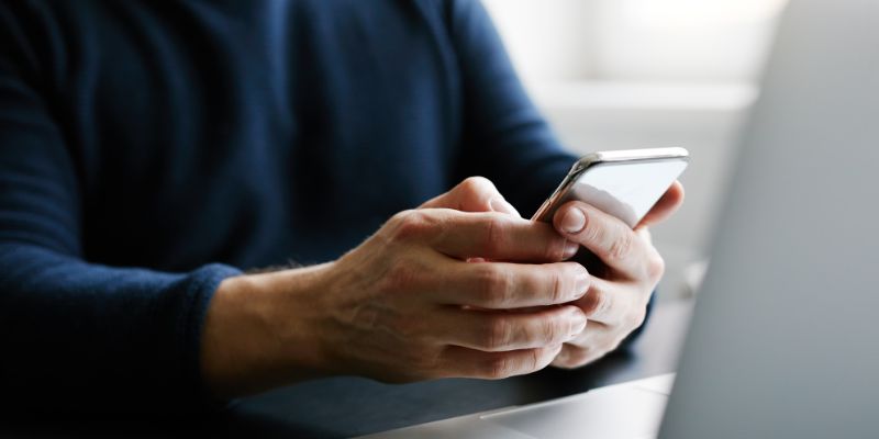 Person using a phone and sat at laptop