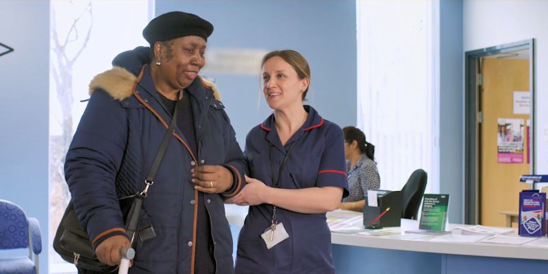 A nurse escorts a patient inside a hospital