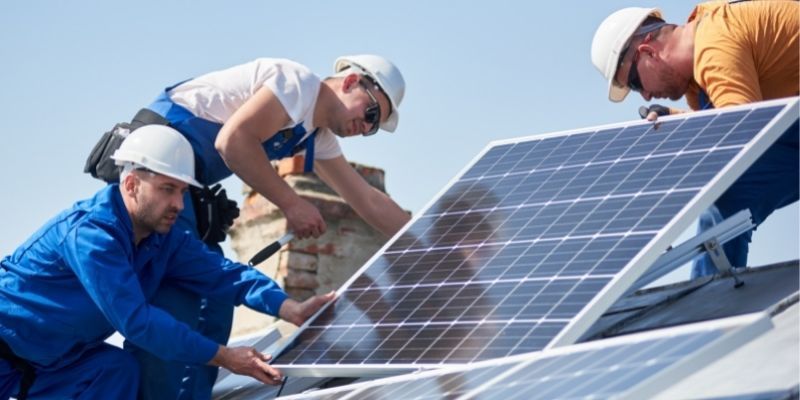 Three workers installing solar panels