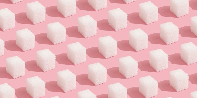 Sugar cubes lined up in rows on a pink background