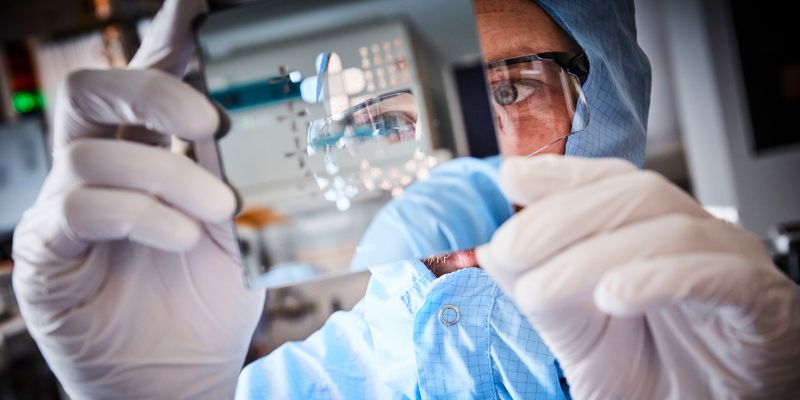 A technician examines a metal component in a lab.