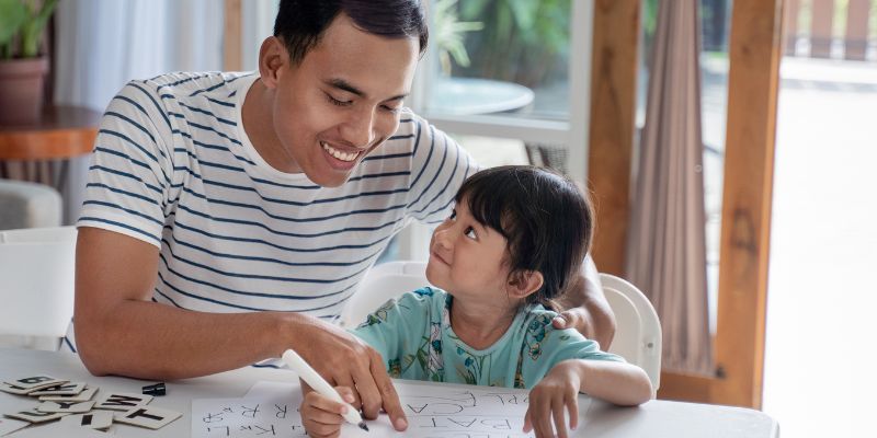 A young child smiles up at their father.